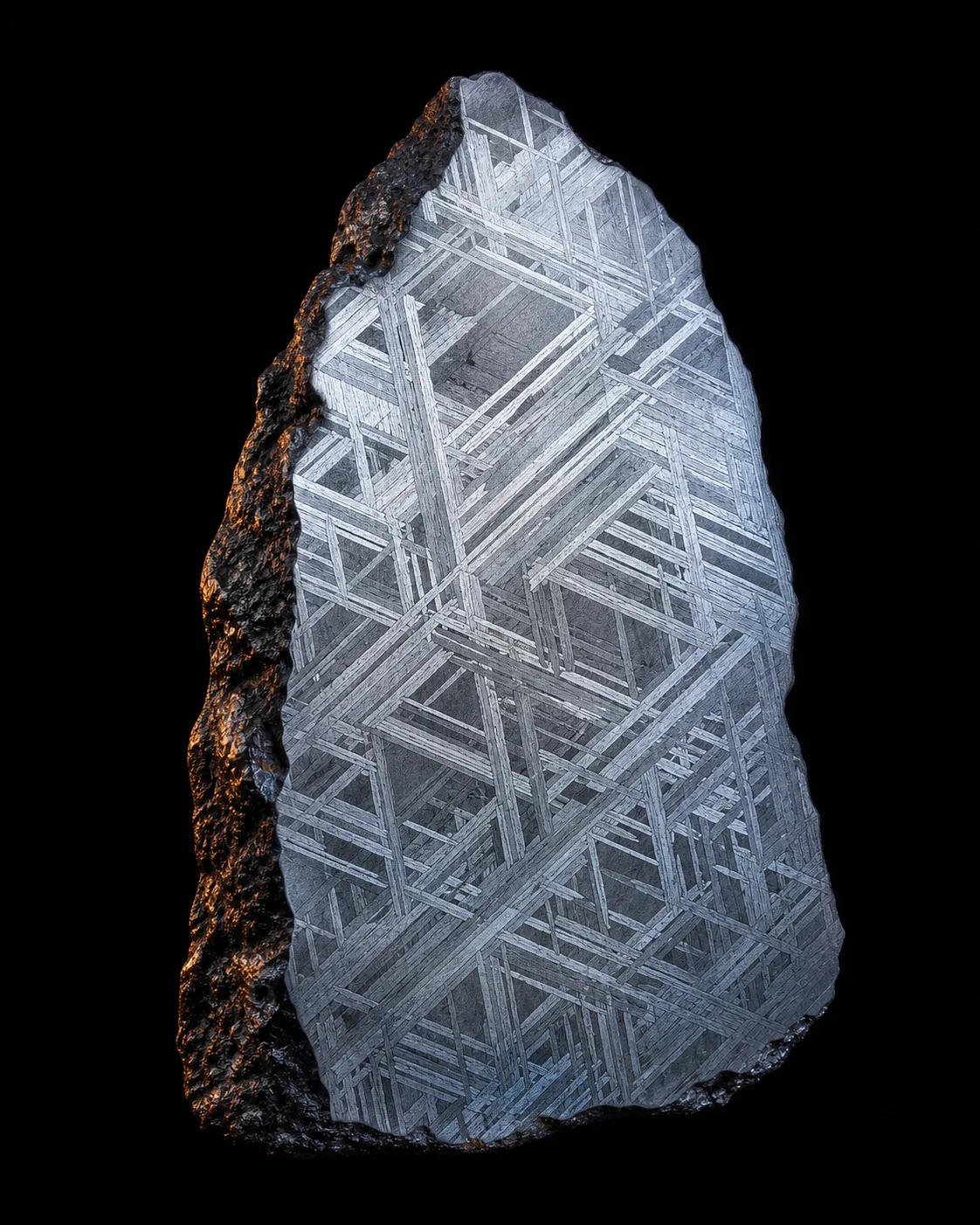 An etched iron meteorite slice revealing a crystalline Widmanstätten lattice, lit against black